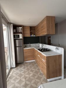 a kitchen with wooden cabinets and a stainless steel refrigerator at Le Domaine des Pins in Saint-Hilaire-de-Riez
