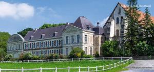 a large building with a fence in front of it at Confortable Maison in Les Rues-des-Vignes