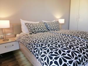 a bedroom with a bed with a black and white comforter at Ferienwohnung Vogelkieker in Schillig +11 photos