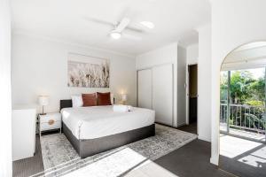 a white bedroom with a bed and a balcony at Byron Beachside 2 in Byron Bay +32 photos