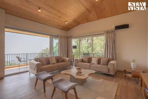 un salon avec un canapé et une table dans l'établissement StayVista at Glass Forest with Bonfire, BBQ, à Mussoorie