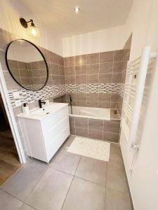 a bathroom with a sink and a tub and a mirror at La Maison de Mélou in Troarn