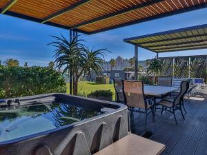 a hot tub on a deck with a table and chairs at Beachwood Cottage in Gordonʼs Bay