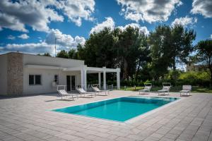 a swimming pool with chairs and a house at Likehome Ponente Levante 2 Ville luxury Pool 12pxs in Taranto