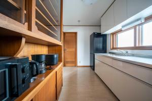 札幌市にあるE-US Naebo HOUSEの白いキャビネットと黒い冷蔵庫のあるキッチン
