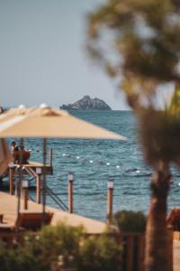 a view of a beach with an umbrella and the ocean at Ruins Luxury Resort - Adults Only in Yalıkavak