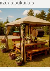 a picnic table under an umbrella with baskets and flowers at Šilas in Degučiai