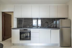 a kitchen with white cabinets and a stainless steel refrigerator at Apartments Linda in Prizba