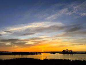 a sunset over a body of water with the sun setting at Ferienwohnung "Wallheckenblick Schatteburg", 95159 in Rhauderfehn