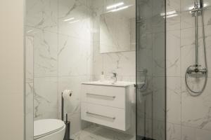a white bathroom with a toilet and a shower at Apartments Linda in Prizba +33 photos