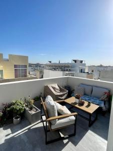 a patio with a couch and a table on a balcony at Cozy loft-duplex penthouse in Il-Gżira