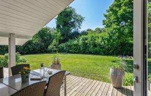 a patio with a table and chairs and a yard at Awesome Home In Rudkøbing With Sauna in Spodsbjerg