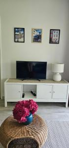 ein Wohnzimmer mit einem TV und einer Vase aus Blumen in der Unterkunft Pause Luzienne à deux pas de la plage in Saint-Jean-de-Luz