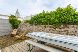 a picnic table and a chair on a patio at Bel appartement Peuplier in Dolus-d'Oléron
