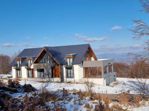 a house with a black roof in the snow at Panorama Budești in Budeşti
