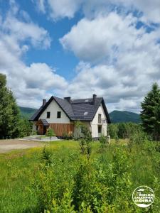 a white house with a black roof on a field at Pod Wielką Zalesioną Górą in Wetlina