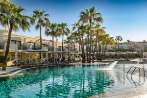 a swimming pool with palm trees and a fountain at Valentin Star Menorca - Adults Only in Cala'n Bosch