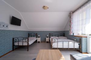 a bedroom with two beds and a table and a tv at Chata Jana in Łeba +10 photos