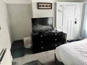 a bedroom with a tv on a dresser with a bed at Beautiful three bedroom house in Liverpool