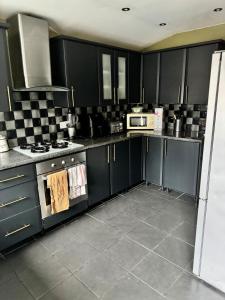a kitchen with black cabinets and a stove and microwave at Beautiful three bedroom house in Liverpool