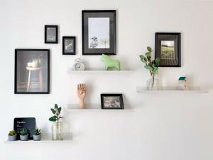 Una pared con estantes blancos con cuadros y plantas. en A nette Wohnung, en Füssen