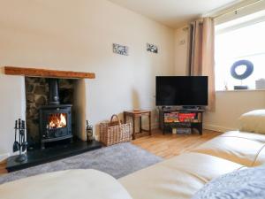 a living room with a fireplace and a television at Rose Cottage in Buxton