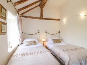 two beds in a room with white walls at Rose Cottage in Buxton