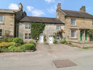 an old stone house with a driveway in front of it at Rose Cottage in Buxton