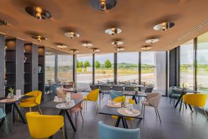 a restaurant with tables and chairs and windows at Viale Boutique Hotel in Villány