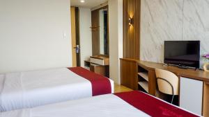 a hotel room with two beds and a desk with a television at Long Beach Hotel Pangandaran in Pangandaran