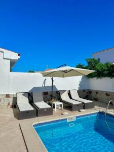 a swimming pool with chairs and an umbrella next to a swimming pool at Chalets con piscinas privadas junto al mar in Cala en Bosc