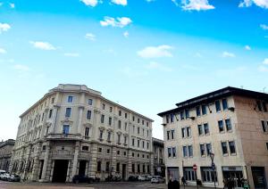 two tall buildings on a city street with a blue sky at Foresteria Juvarra in Mantova