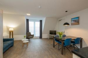 a living room with a blue couch and a table at Welcome in - Aparthotel Zoutelande, studio's en app voor 2-6 pers - 50m van het strand in hartje centrum in Zoutelande