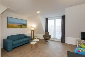 a living room with a blue couch and a chair at Welcome in - Aparthotel Zoutelande, studio's en app voor 2-6 pers - 50m van het strand in hartje centrum in Zoutelande