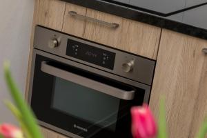 a black oven in a kitchen with pink flowers at Welcome in - Aparthotel Zoutelande, studio's en app voor 2-6 pers - 50m van het strand in hartje centrum in Zoutelande +180 photos