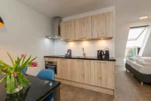 a kitchen with wooden cabinets and a bed in a room at Welcome in - Aparthotel Zoutelande, studio's en app voor 2-6 pers - 50m van het strand in hartje centrum in Zoutelande