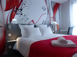 um quarto com uma cama vermelha e branca com toalhas em L'AEROGARE Amboise em Amboise