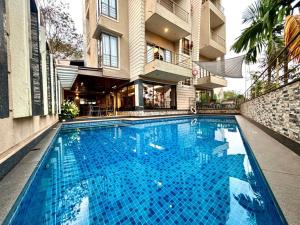 a large blue swimming pool in front of a building at Merlot Suites in Porvorim