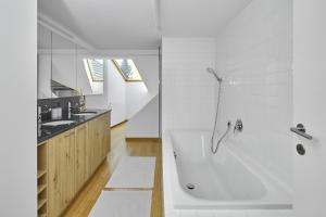 un bagno bianco con vasca e lavandino di Außergewöhnliches Loft am Pfänderhang mit Seeblick a Lochau