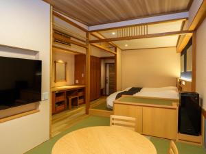 a bedroom with a bed and a tv and a table at Mizunoto Reopening on April 1, 2025 in Hakone