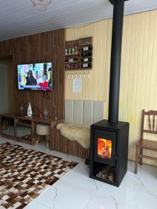 a living room with a fireplace and a tv at Casa- Encanto da Praça in Urupema