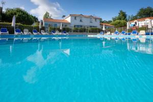 a large swimming pool with chairs and blue water at Résidence Odalys Le Domaine de l'Océan in Saint-Brévin-lʼOcéan
