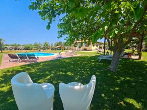 アルゲーロにあるLarge Villa Mediterranea in the heart of Coral Shore with swimming pool large garden with palm treesの芝生に白い椅子が置かれた庭の景色