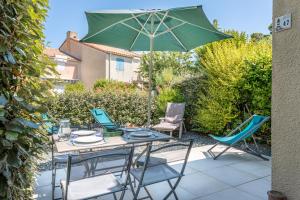 eine Terrasse mit Tisch und Stühlen und einem Sonnenschirm in der Unterkunft La belle petite maison d'Oléron in Dolus-d'Oléron
