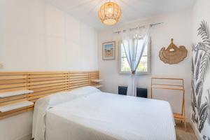 ein Schlafzimmer mit einem weißen Bett und einem Fenster in der Unterkunft La belle petite maison d'Oléron in Dolus-d'Oléron