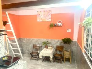 a table and chairs in a room with an orange wall at MaryJun LN Loft Room in Kon Rung (1)