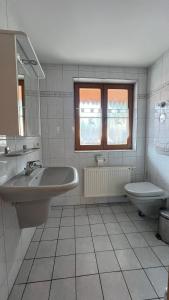 a white bathroom with a sink and a toilet at Wichtel Haus in Oberau +4 photos