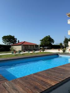 a swimming pool with a wooden deck and a house at Spilaio at Meteora in Kalabaka