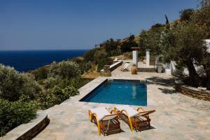 a swimming pool with chairs and the ocean in the background at Villa Riza in Apróvaton