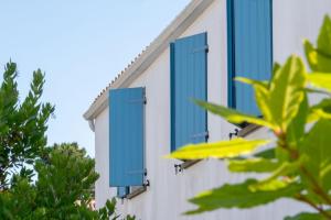 a building with blue shutters on the side of it at Résidence Prestige Odalys Le Domaine des Pins in Noirmoutier-en-l'lle